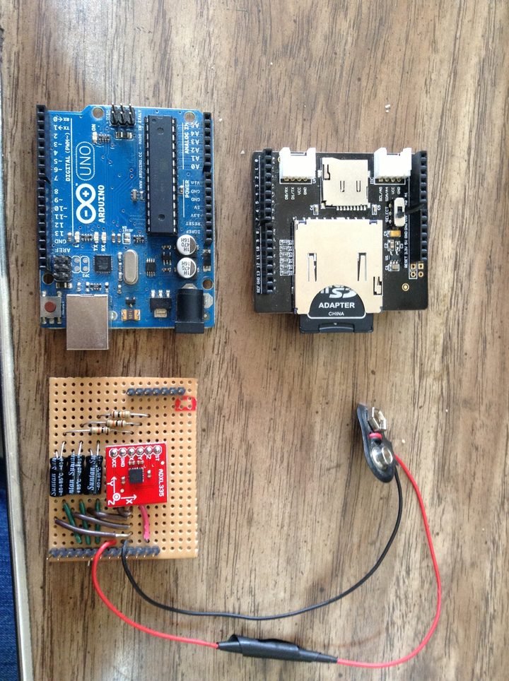 The full kit laid out: an Arduino Uno, an SD card shield with a microSD adapter inserted, the ADXL335 filter perfboard, and a 9V battery with clip