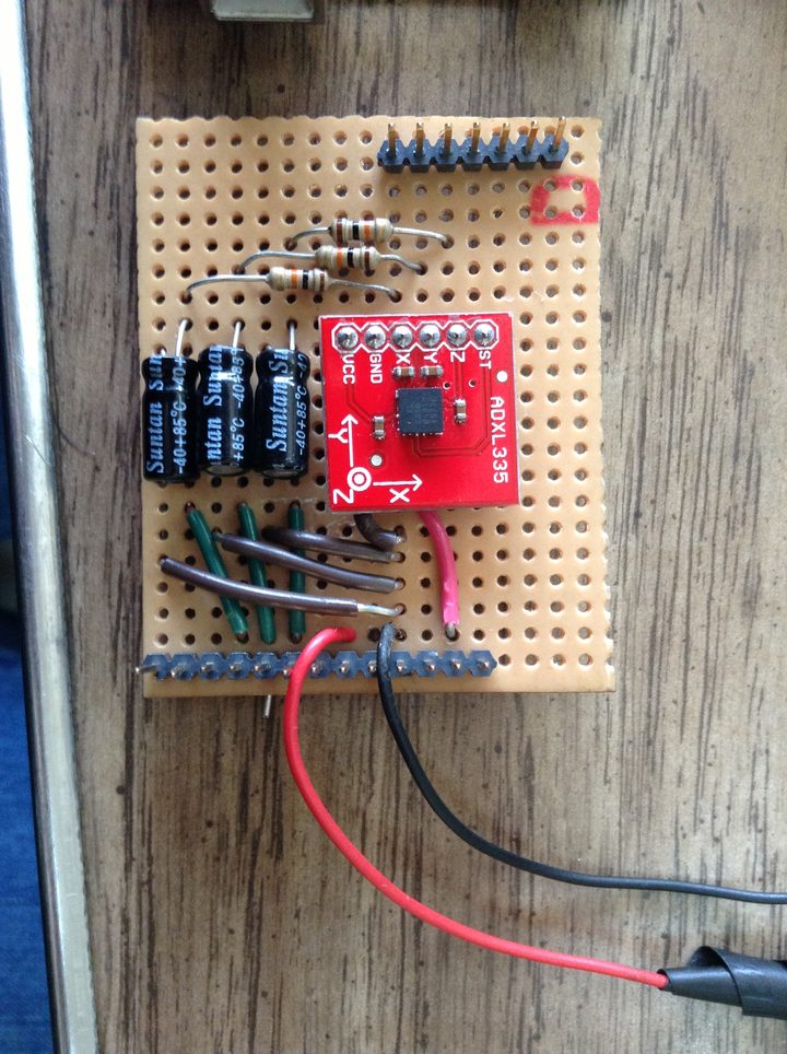 Close-up of the ADXL335 breakout board on a perfboard, wired to three RC filter resistors and three electrolytic bypass capacitors
