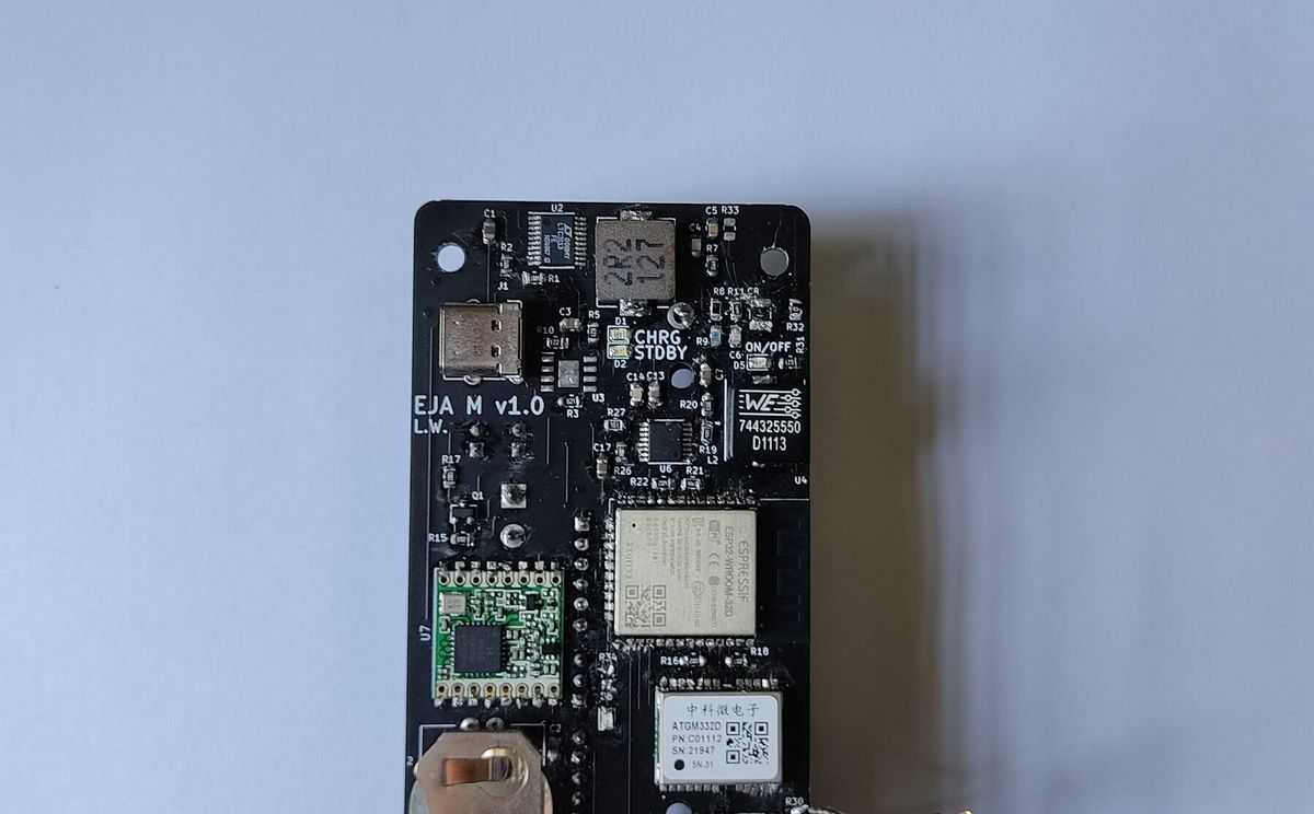 Top of the assembled EJA M v1.0 board: USB-C connector, CHRG/STDBY and ON/OFF indicator LEDs, the ESP32-WROOM-32D, the RFM95W LoRa module, the ATGM332D GPS module and a coin-cell holder