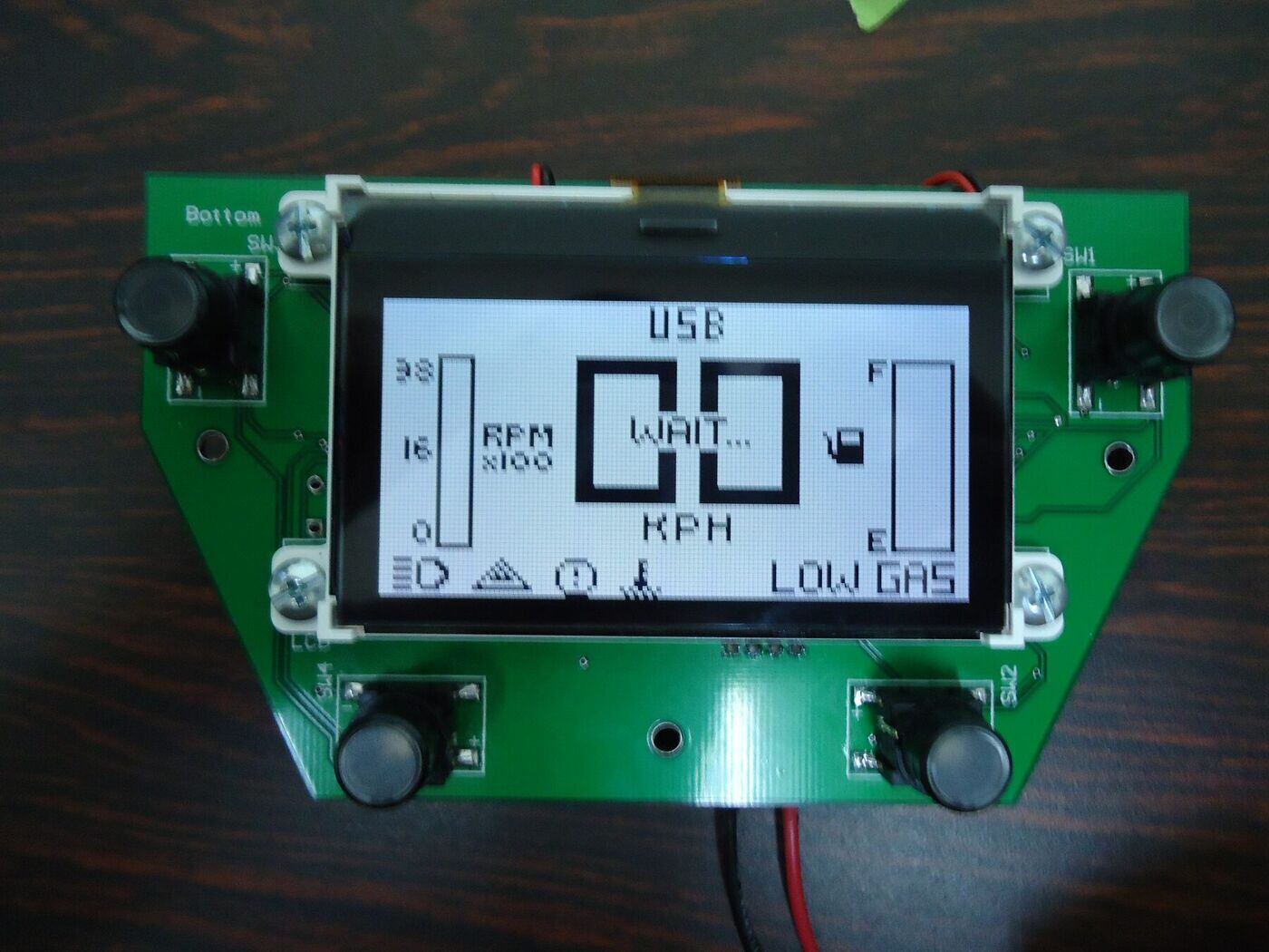 The LCD showing the RPM and fuel bars, the KPH readout, and the row of tell-tale icons along the bottom with a LOW GAS warning