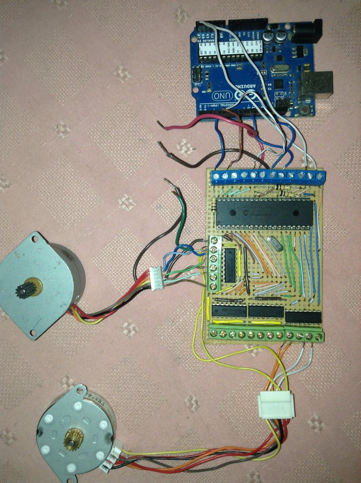 An Arduino Uno wired to a custom PIC perfboard with terminal blocks, alongside two unipolar stepper motors, during bench testing