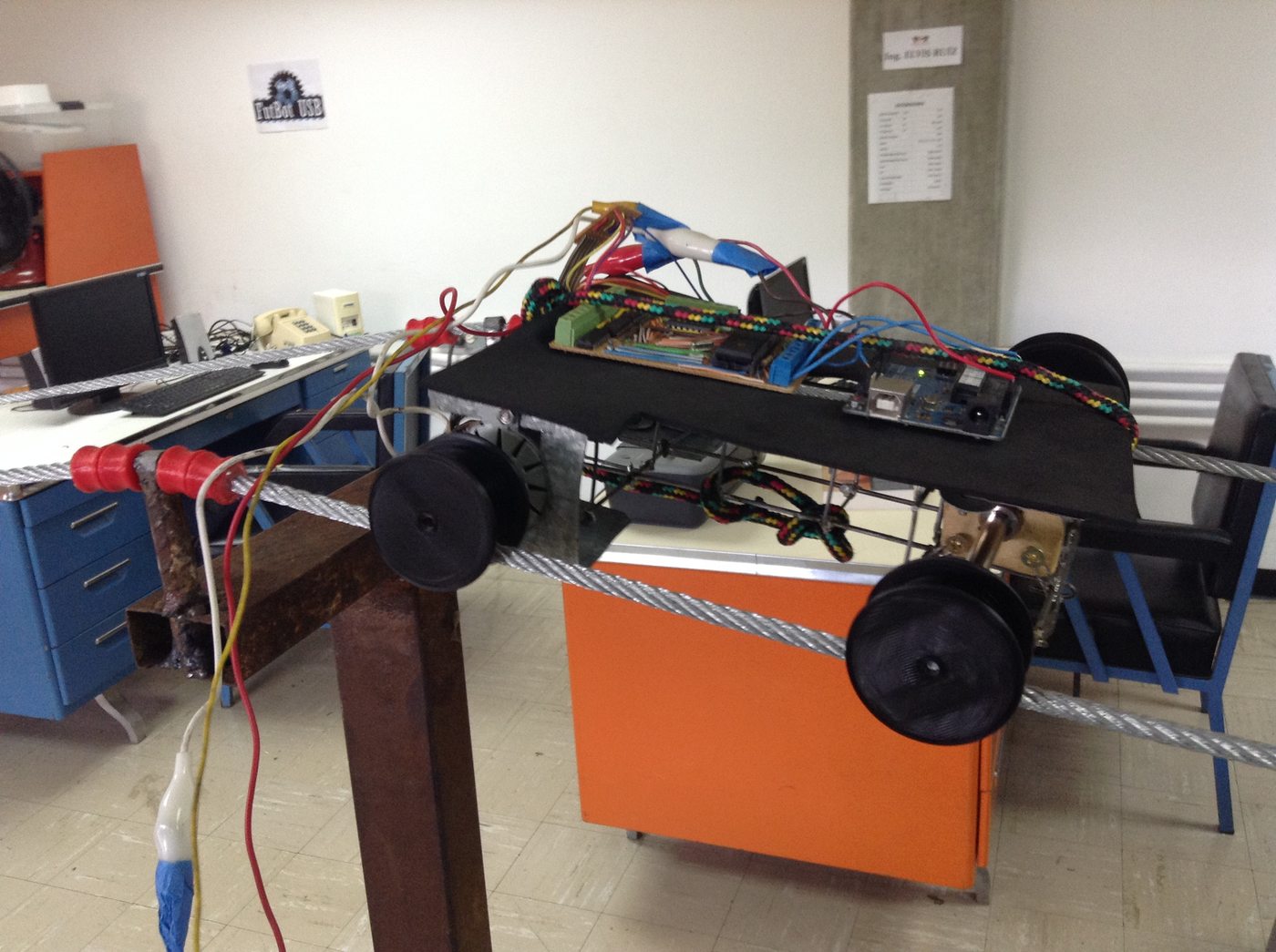 E-wanna semi-assembled on the lab's cable rig, with a FutBot USB team poster visible on the wall behind it