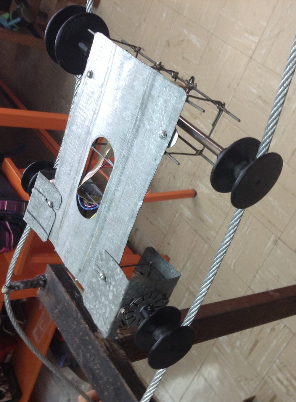 Top-down view of the finished chassis mounted on all four wheels on the cable, showing the sheet-metal deck cutout with wiring passing through